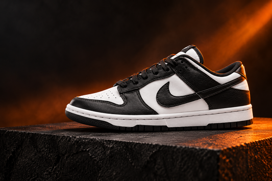 Nike Dunk Low noire et blanche dans une mise en scène éditoriale noir et orange